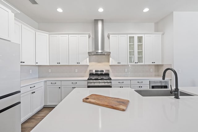 kitchen featuring gas stove, tasteful backsplash, white cabinetry, and wall chimney exhaust hood