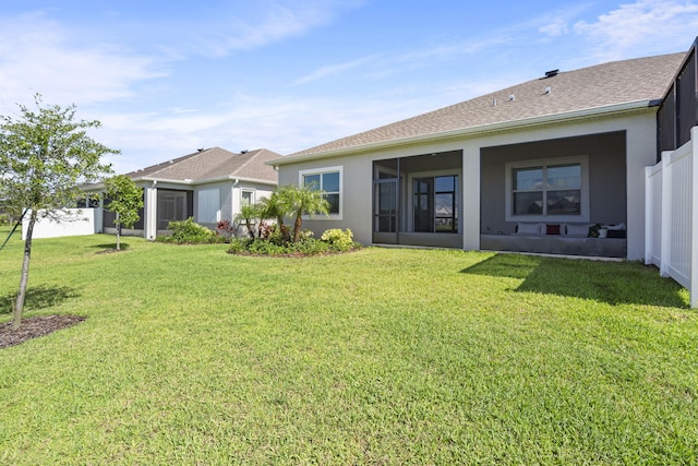 back of property with a sunroom and a lawn