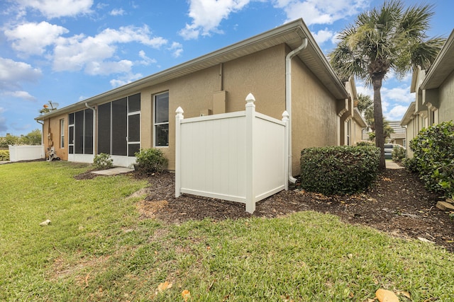 back of property with a sunroom and a lawn