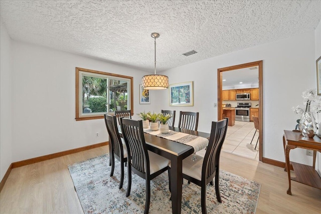 dining space featuring a textured ceiling and light wood-type flooring