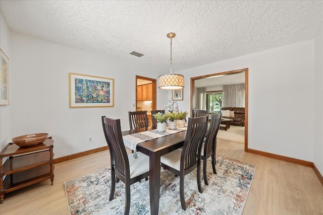 dining space featuring a textured ceiling and light hardwood / wood-style flooring