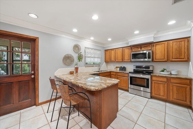 kitchen featuring light stone countertops, light tile patterned floors, appliances with stainless steel finishes, a kitchen bar, and kitchen peninsula