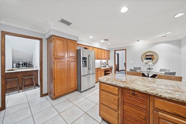 kitchen with stainless steel fridge with ice dispenser, light tile patterned floors, light stone countertops, and ornamental molding