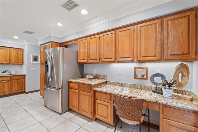 kitchen with light stone counters, ornamental molding, light tile patterned floors, built in desk, and stainless steel fridge with ice dispenser