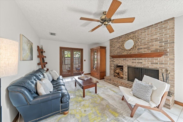 tiled living room with ceiling fan, french doors, a textured ceiling, and a brick fireplace