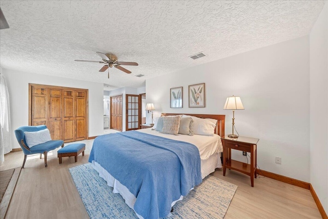 bedroom with ceiling fan, light hardwood / wood-style floors, and a textured ceiling