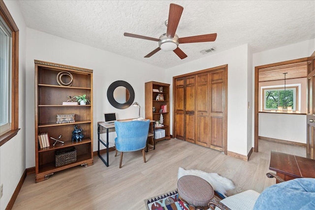 office featuring ceiling fan, light hardwood / wood-style flooring, and a textured ceiling