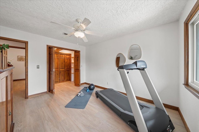 workout area with ceiling fan, a textured ceiling, and light hardwood / wood-style flooring