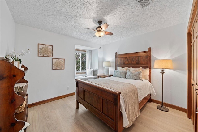 bedroom with ceiling fan, light hardwood / wood-style floors, a textured ceiling, and a closet