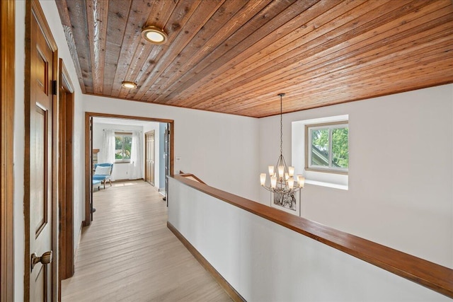 hall with light hardwood / wood-style floors, wood ceiling, and an inviting chandelier