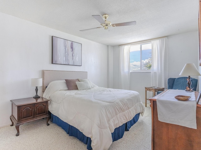 bedroom with ceiling fan, light colored carpet, and a textured ceiling