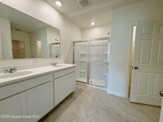 bathroom featuring tile patterned floors, a shower with door, and vanity