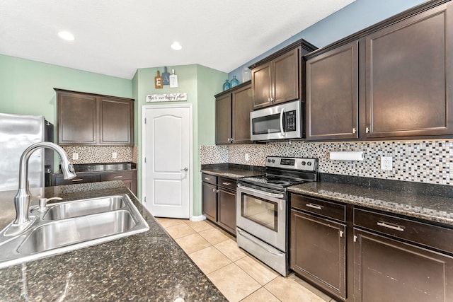 kitchen with sink, dark brown cabinetry, light tile patterned floors, appliances with stainless steel finishes, and tasteful backsplash