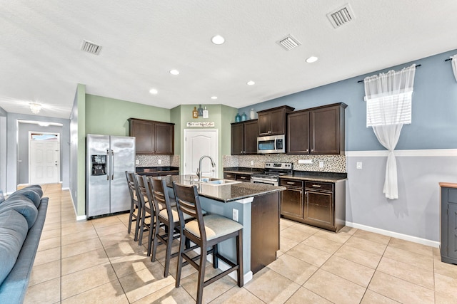 kitchen featuring sink, appliances with stainless steel finishes, backsplash, and an island with sink