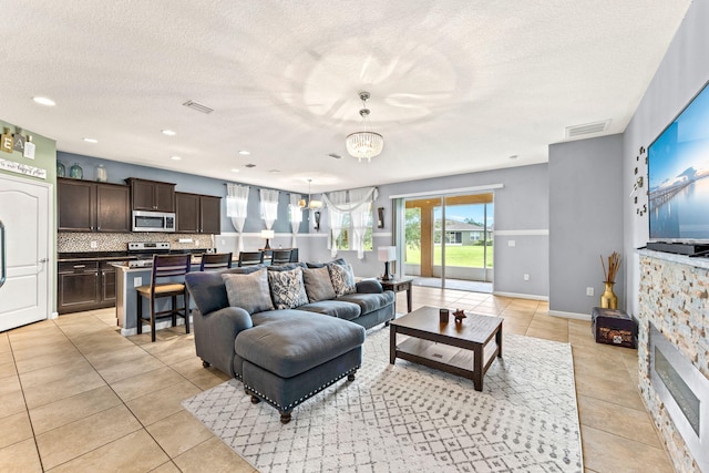 tiled living room featuring a textured ceiling and a chandelier