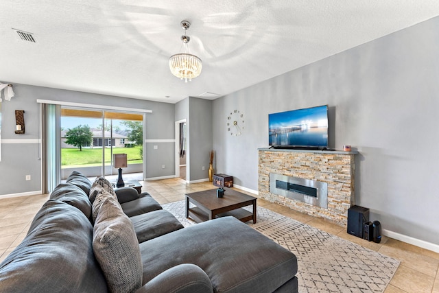 tiled living room featuring a chandelier, a fireplace, and a textured ceiling