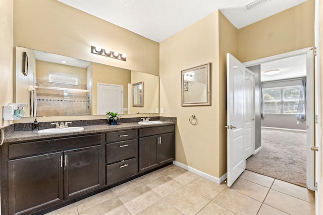 bathroom with vanity, a textured ceiling, walk in shower, and tile patterned floors