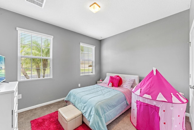 bedroom featuring a textured ceiling, multiple windows, and light colored carpet