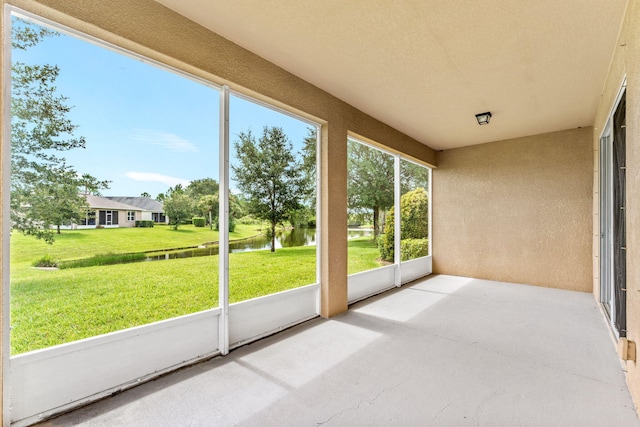 unfurnished sunroom featuring a water view