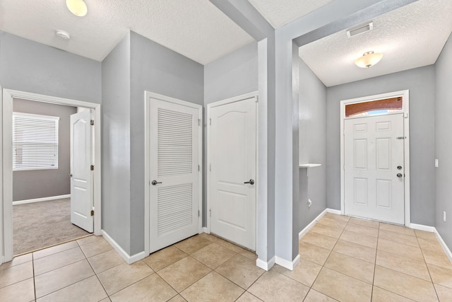 entrance foyer with a textured ceiling and light tile patterned flooring