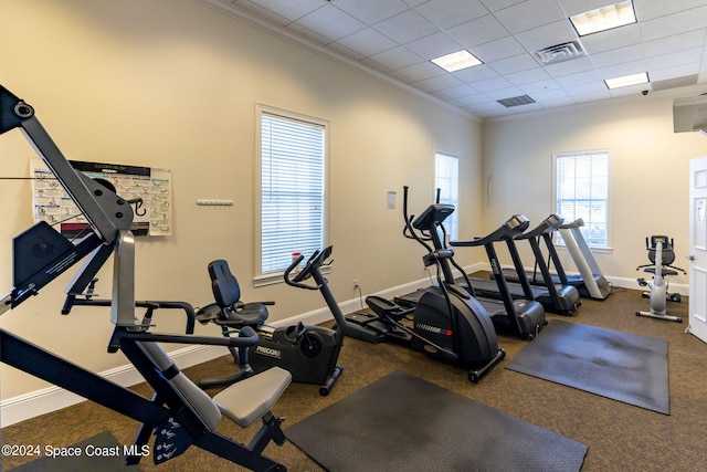 exercise room with ornamental molding and a drop ceiling