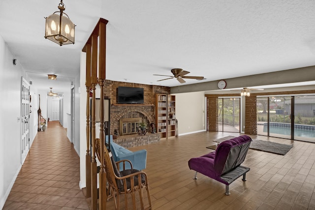 living room with a brick fireplace, ceiling fan with notable chandelier, hardwood / wood-style floors, and a textured ceiling