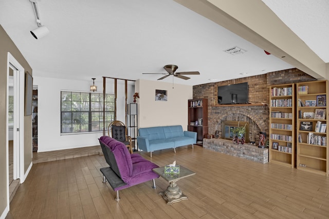 living room with ceiling fan, a brick fireplace, and light wood-type flooring