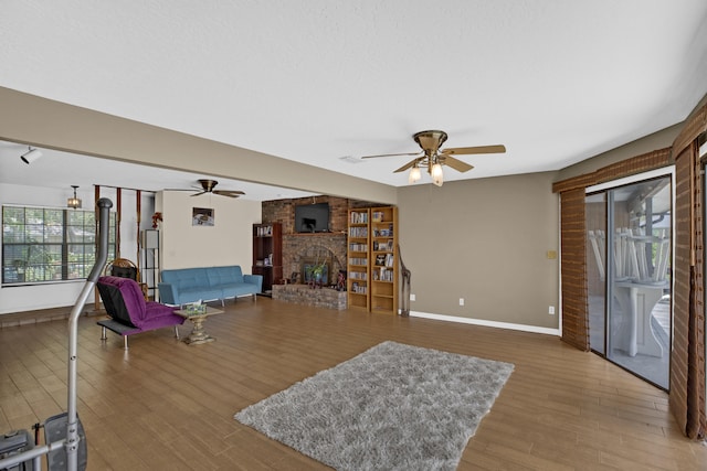 living room with ceiling fan, a large fireplace, and hardwood / wood-style floors