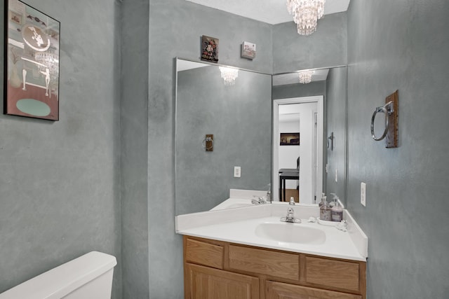 bathroom with vanity, toilet, and a chandelier