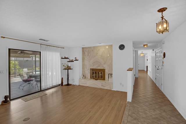 unfurnished living room featuring a premium fireplace, hardwood / wood-style floors, and a notable chandelier