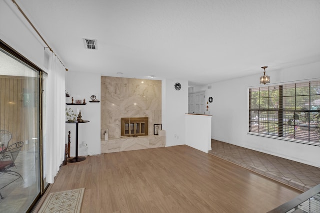 unfurnished living room featuring light wood-type flooring, an inviting chandelier, and a fireplace