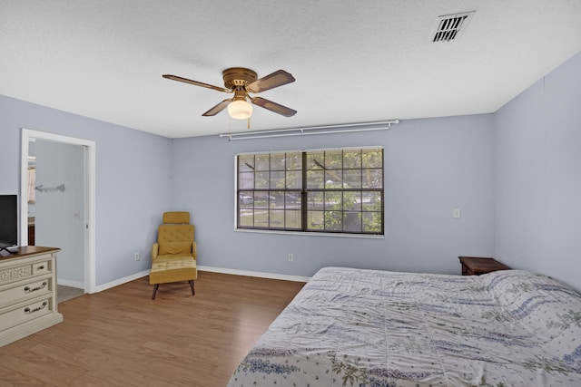 bedroom featuring ceiling fan, dark hardwood / wood-style floors, and a textured ceiling