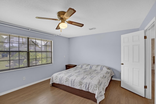 bedroom with ceiling fan, dark hardwood / wood-style flooring, and a textured ceiling