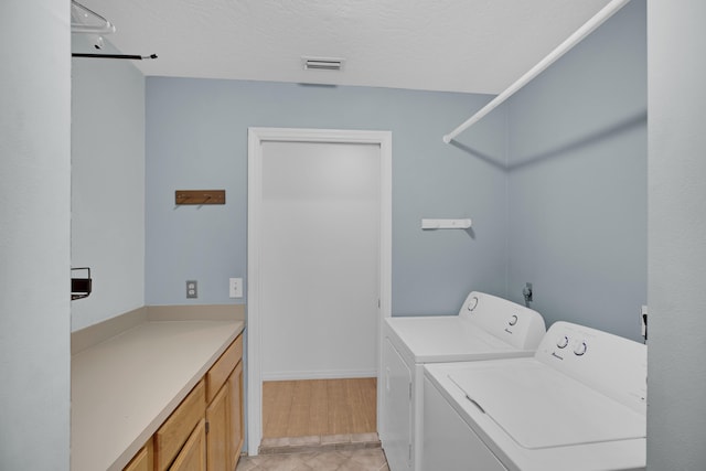 laundry room with cabinets, separate washer and dryer, and a textured ceiling