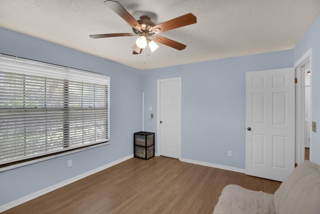 interior space with ceiling fan, light hardwood / wood-style floors, and a textured ceiling