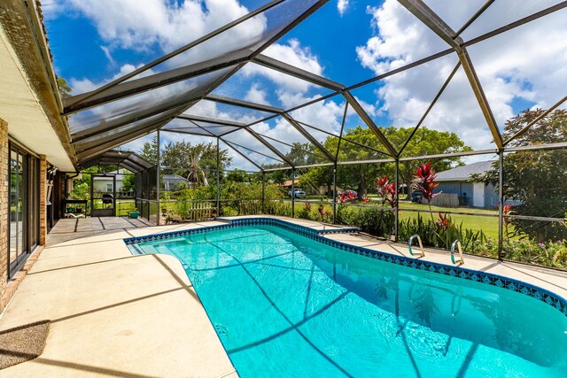 view of pool featuring glass enclosure and a patio area