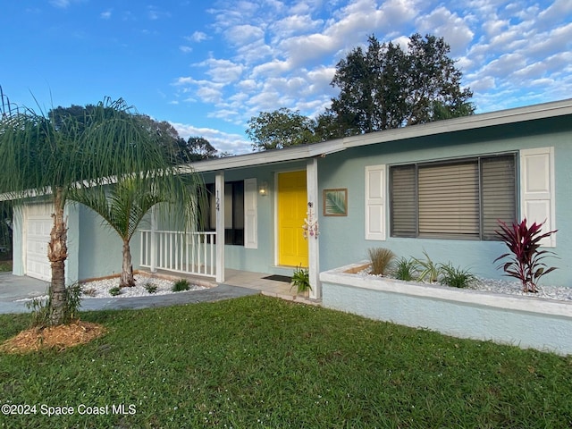 single story home with a porch, a garage, and a front lawn