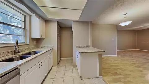 kitchen featuring decorative light fixtures, dishwasher, sink, white cabinets, and light tile patterned floors