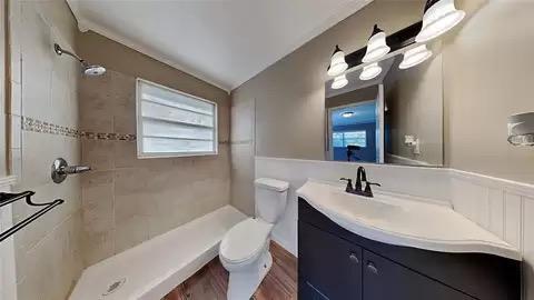 bathroom with vanity, lofted ceiling, toilet, and a tile shower