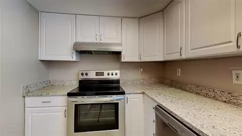 kitchen with light stone counters, white cabinets, and appliances with stainless steel finishes