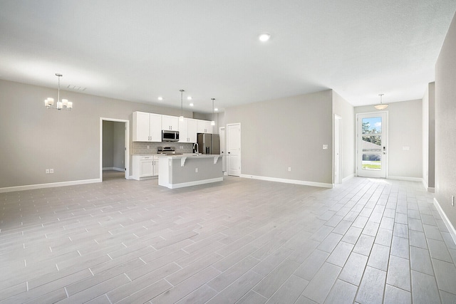 unfurnished living room featuring a chandelier and light wood-type flooring