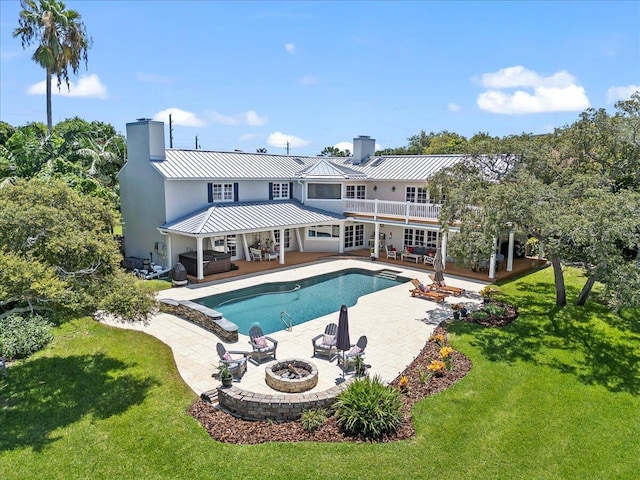 rear view of property with an outdoor living space with a fire pit, a patio area, and a lawn