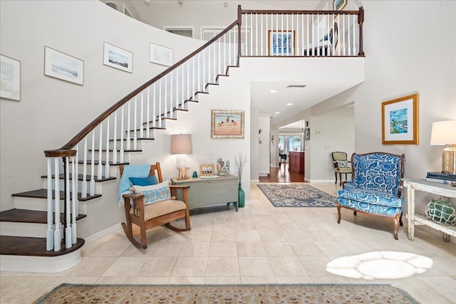 stairway featuring tile patterned flooring and a high ceiling