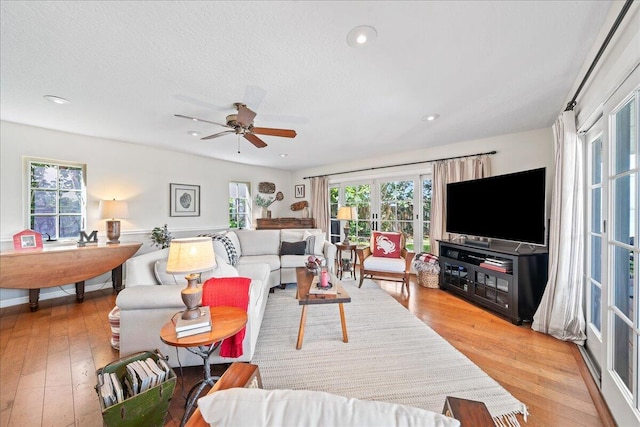 living room featuring a textured ceiling, light hardwood / wood-style flooring, and ceiling fan