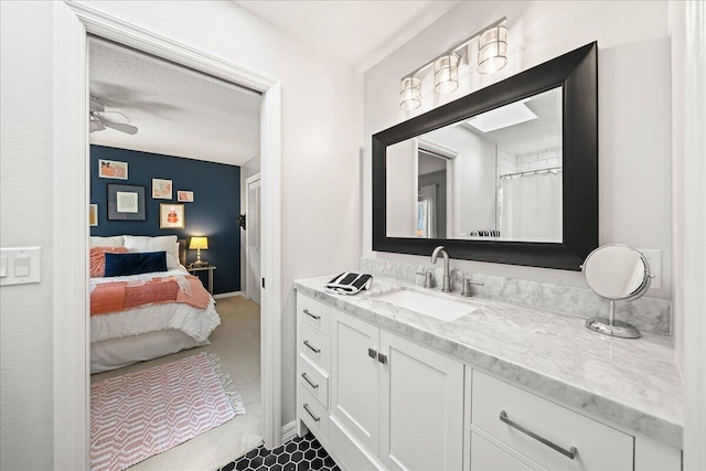 bathroom with ceiling fan, vanity, and a textured ceiling