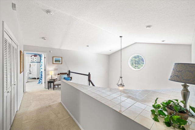 hallway featuring light carpet, a textured ceiling, and vaulted ceiling