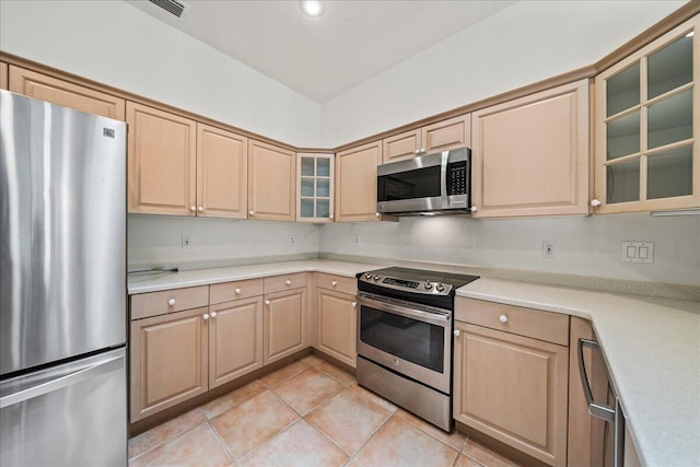 kitchen featuring light brown cabinetry, stainless steel appliances, and light tile patterned floors