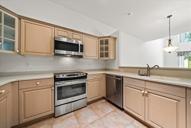 kitchen featuring light brown cabinets, sink, light tile patterned floors, appliances with stainless steel finishes, and decorative light fixtures