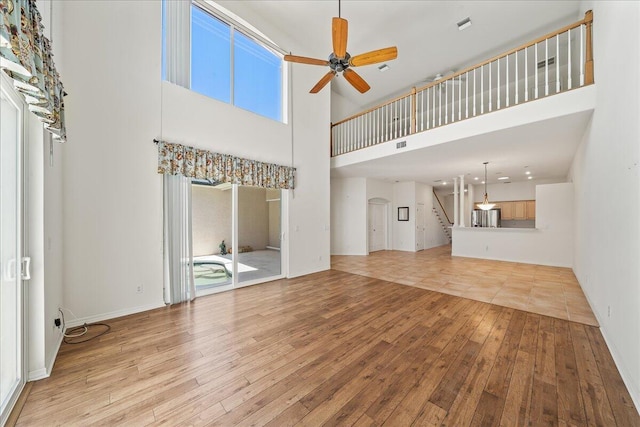 unfurnished living room with a high ceiling, light hardwood / wood-style flooring, and ceiling fan