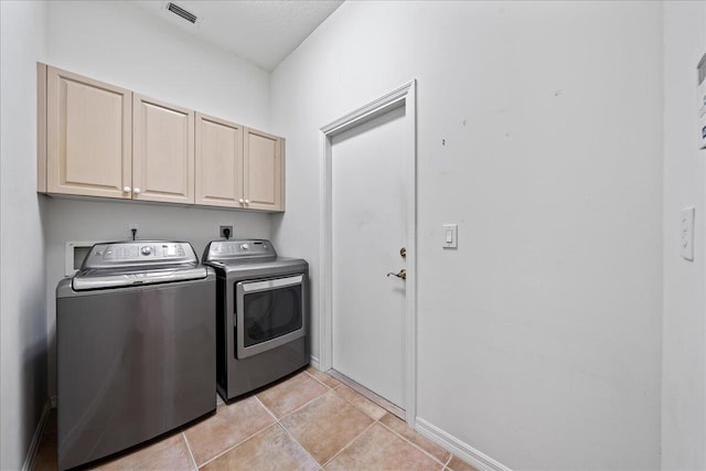 laundry room with light tile patterned floors, cabinets, and independent washer and dryer